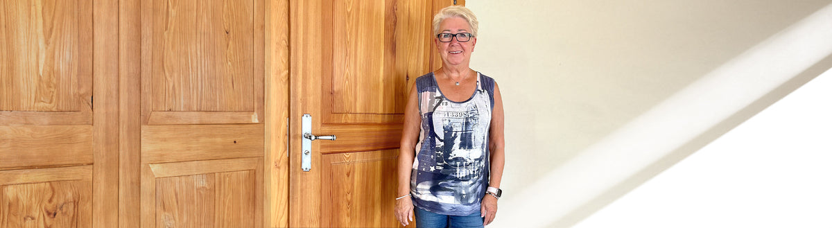 Gaby (67) nach ihrer Gewichtsabnahme mit Precon vor einer Holztür