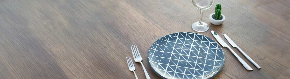 Leerer Teller mit Besteck und Glas auf einem Holztisch als Symbol für Hunger