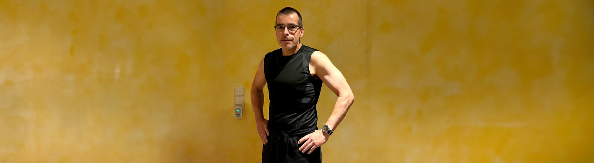 Christian (52) nach seiner Gewichtsabnahme mit Precon, sportlich in schwarzem Shirt vor gelber Wand
