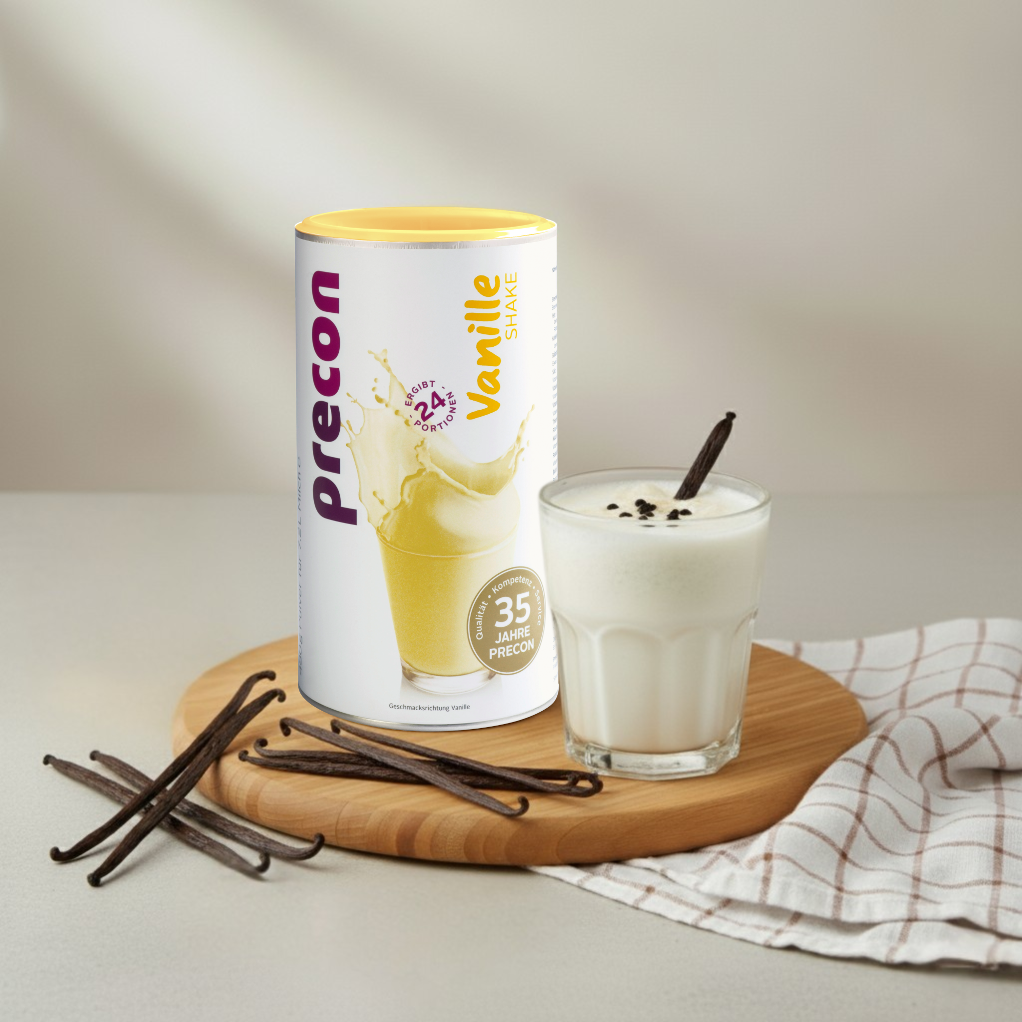 Ein Dose Precon Vanille Shake steht neben einem Glas cremigem Vanille-Shake mit Vanilleschoten auf einem Holzbrett - perfekt für genussvolle Gewichtskontrolle. Dekoriert mit Vanilleschoten und gestreiftem Tuch.