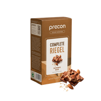 Eine braune Verpackung von „Complete Riegel ChocoBar“ der Anona GmbH, auf deren Vorderseite Schokoladenstückchen, Haferflocken und Mandeln abgebildet sind. Die Verpackung mit deutscher Beschriftung ist vor einem weißen Hintergrund abgebildet.