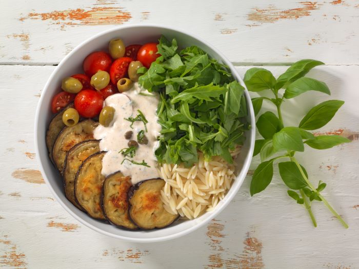 Mediterrane Nudel-Bowl mit Aubergine, Oliven und Kapern-Joghurt-Sauce